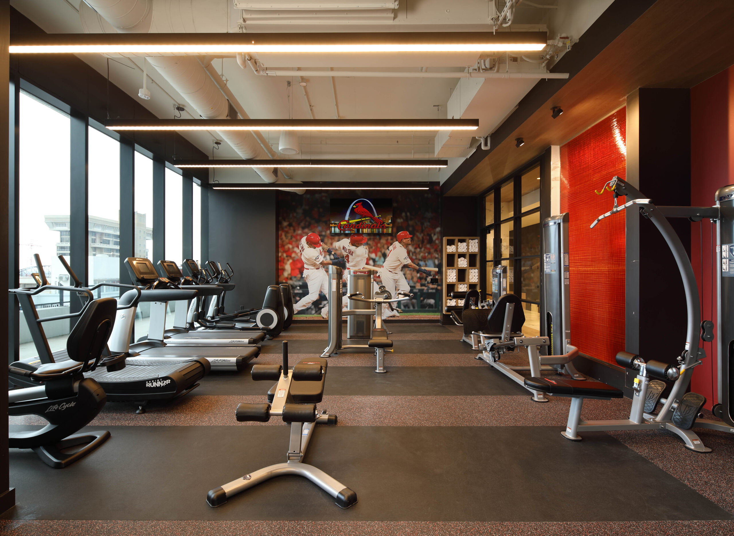 Modern apartment gym with St. Louis Cardinals mural.